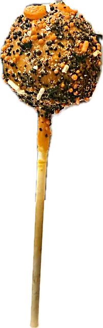 Halloween cake pop in an orange shell covered in orange, black and white sprinkles